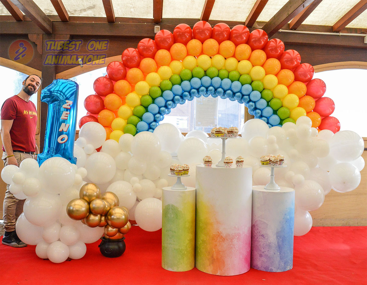 Allestimento tema arcobaleno per feste bambini di 1 anno con cilindri e alzatine